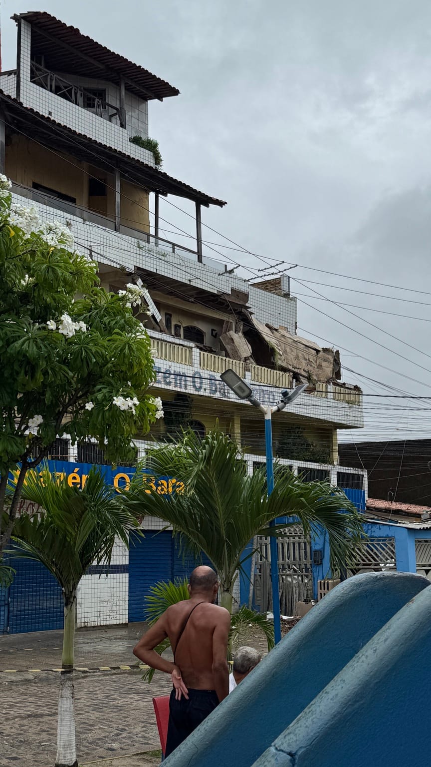 moradores observam condomínio parcialmente destruído após desabamento no bairro do Pilar, em Itamaracá