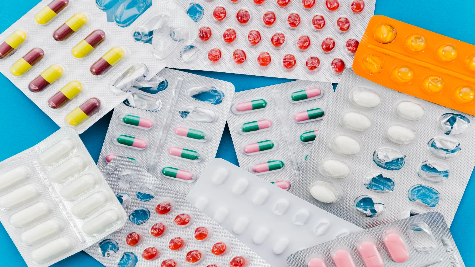 Medicamentos vencidos em diferentes cartelas sobre fundo azul